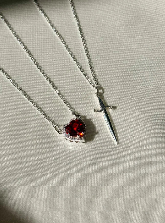 Colar Duplo de Casal ✨ Espada e coração simbolizam proteção e amor eterno. Em aço inoxidável e zircônia, é o presente perfeito para celebrar a união!